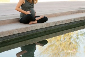 pregnant woman holds belly with serenity pool reflection